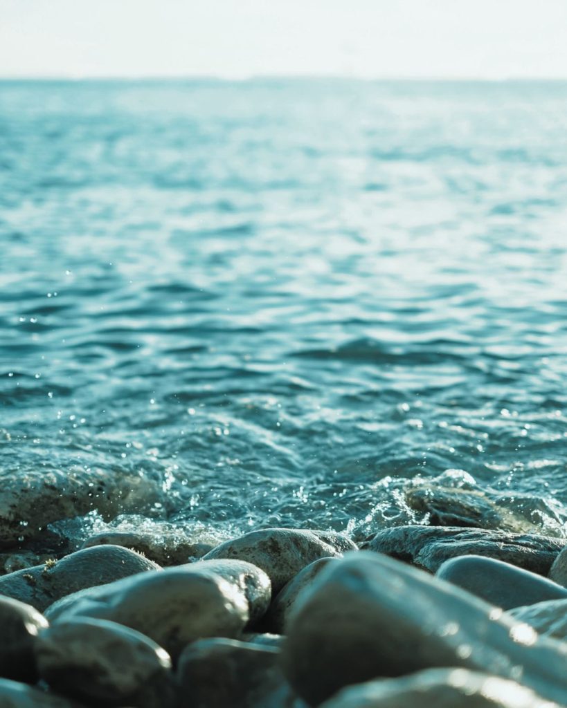 Calming water gently bubbling over smooth pebbles, symbolising grounding and emotional regulation.