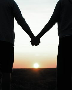 Silhouette of two people holding hands