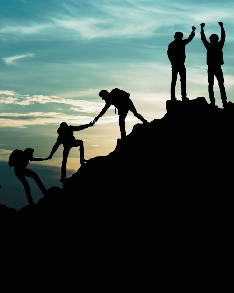 People helping each other up a mountain